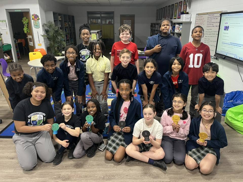 A large group of students, with six in front holding small trophies
