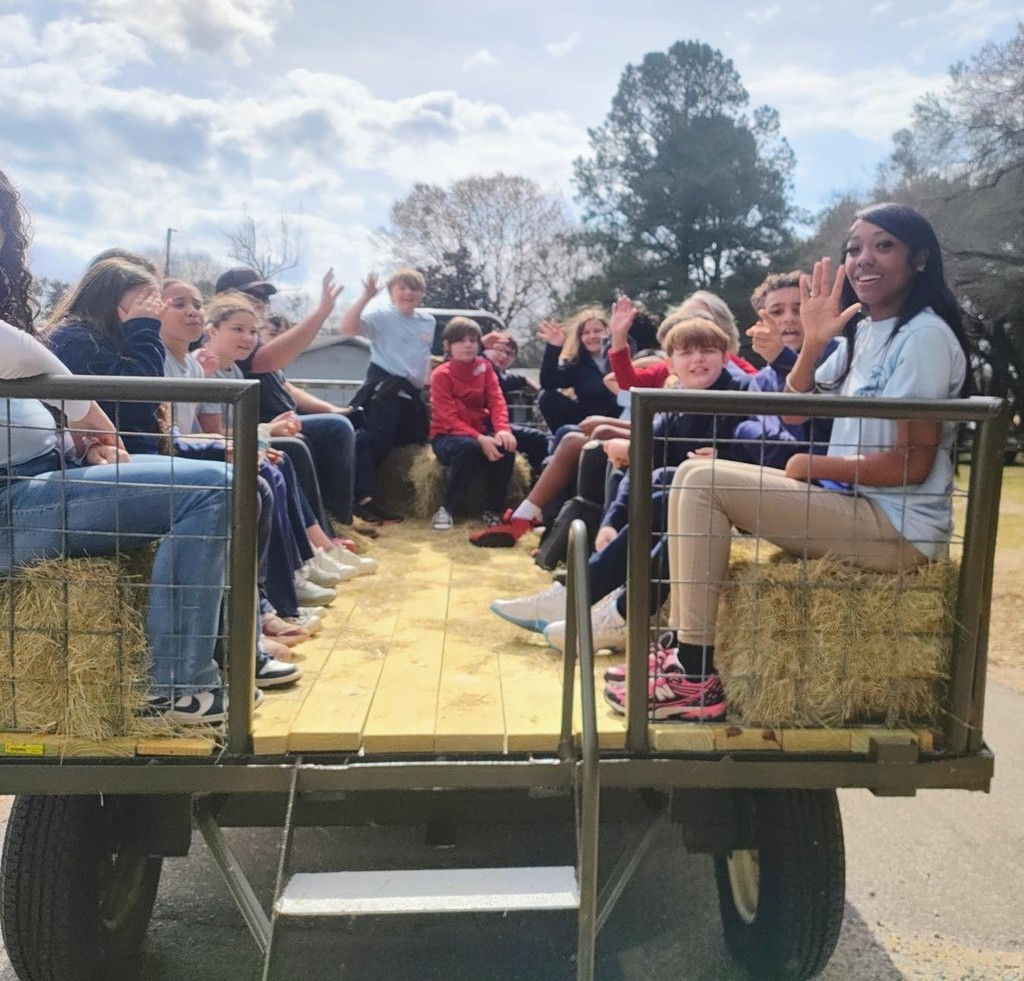Elementary students and a high schooler on a hay ride