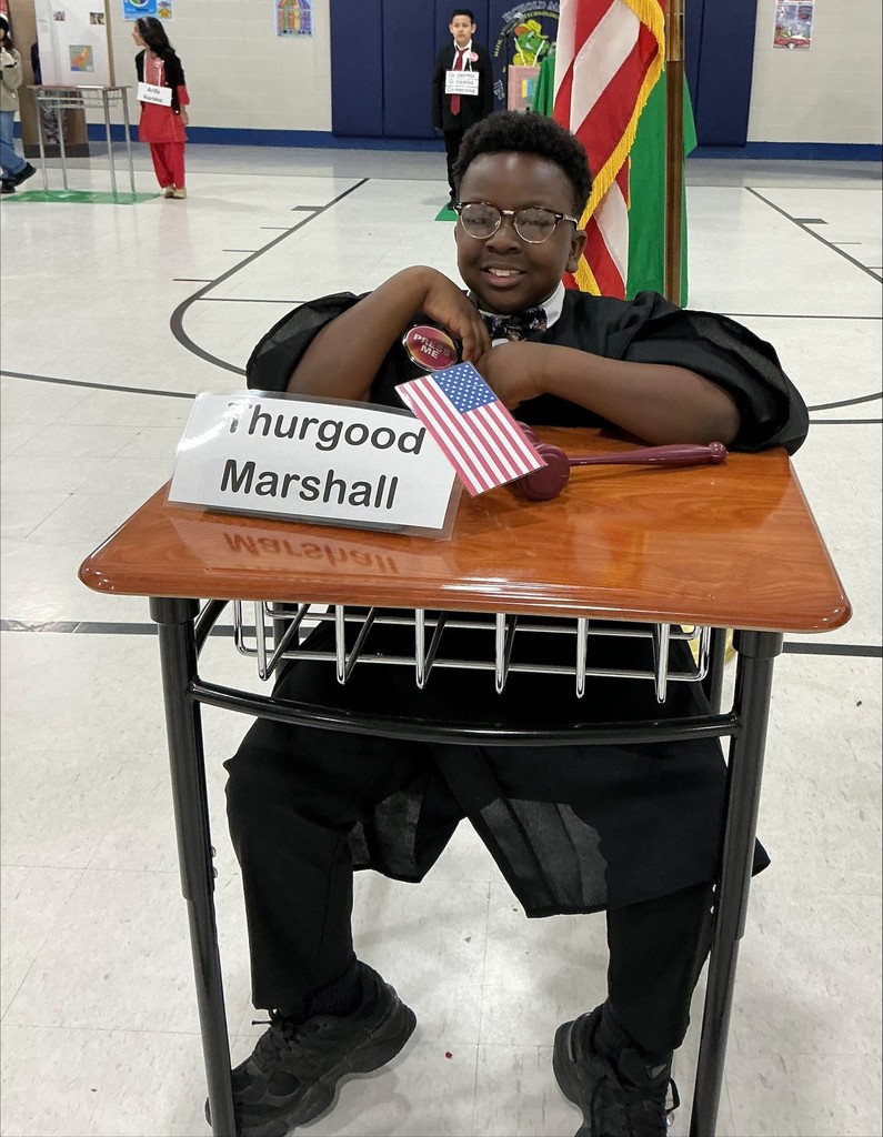 A boy seated at a desk, dressed as Thurgood Marshall
