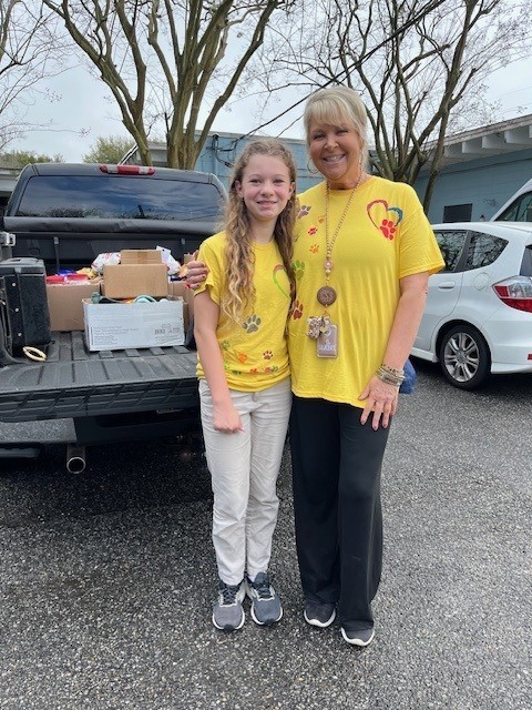 A girl and a woman in yellow T-shirts, standing behind a pickup truck