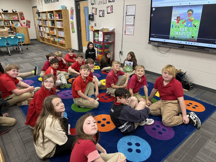 mrs allen’s class in the library sitting on the carpet for read aloud