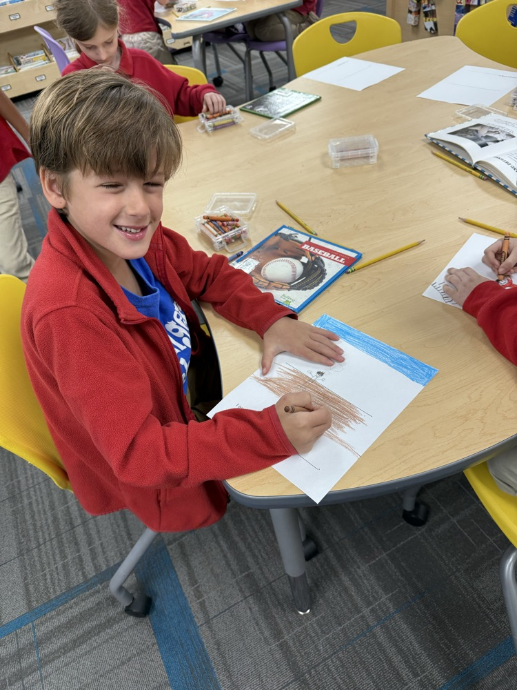 first grader coloring at a table in the library
