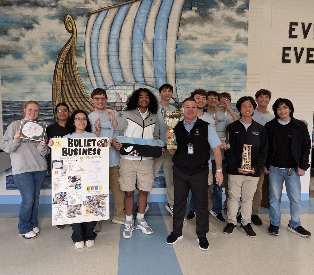 A group of high school students standing with their principal, who is holding a trophy
