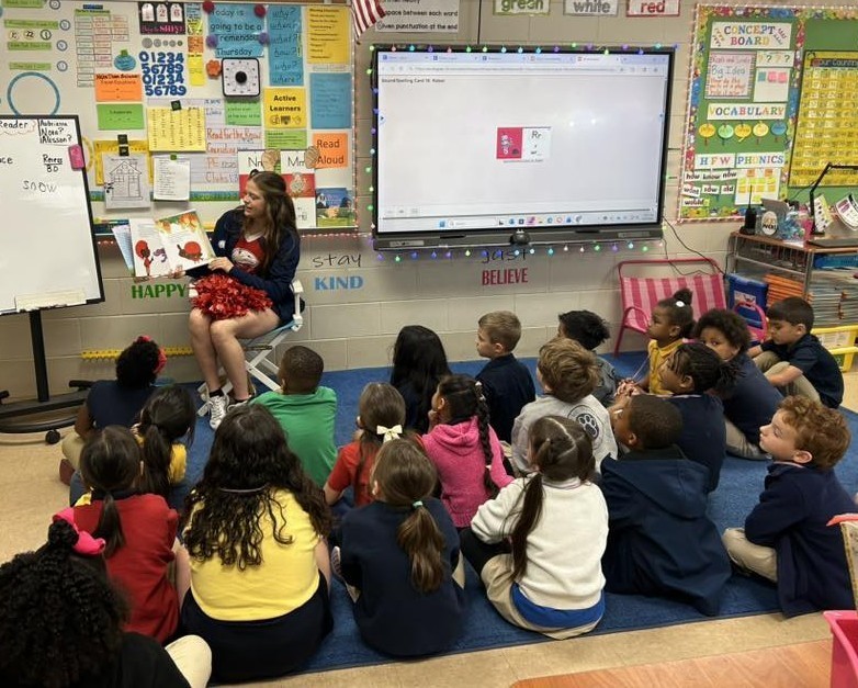 A South Alabama cheerleader reads to a classroom of elementary students