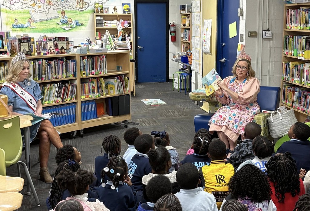 Two women read to a classroom full of children