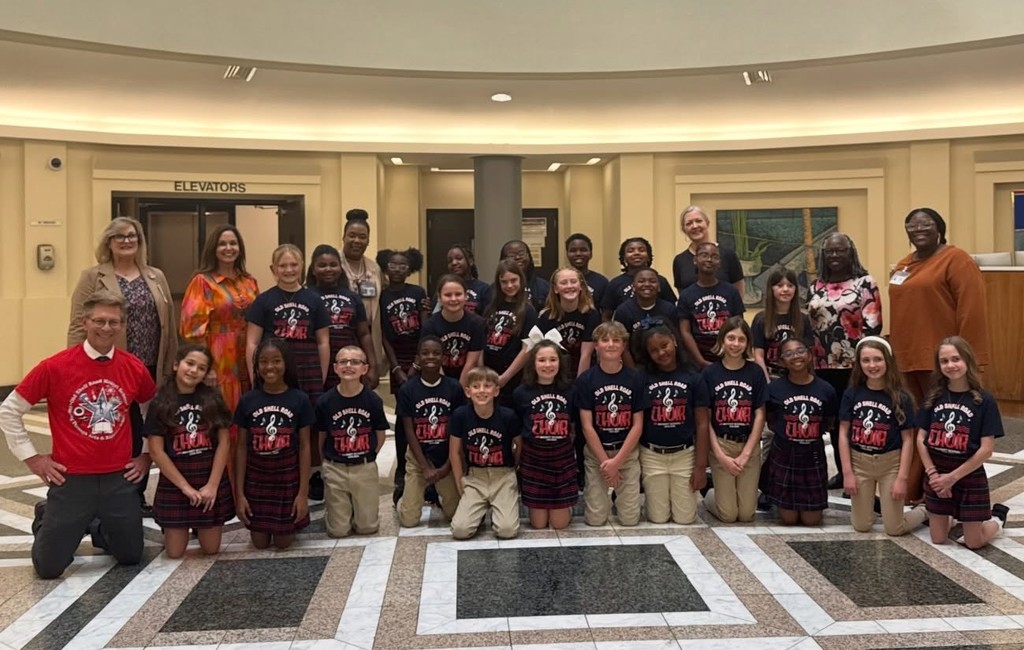 A group of elementary students in blue T-shirts with several adults