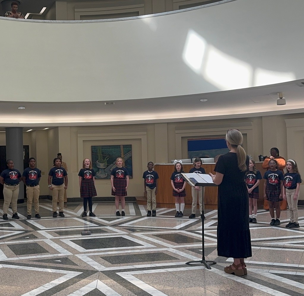 Students singing, while their choir teacher directs