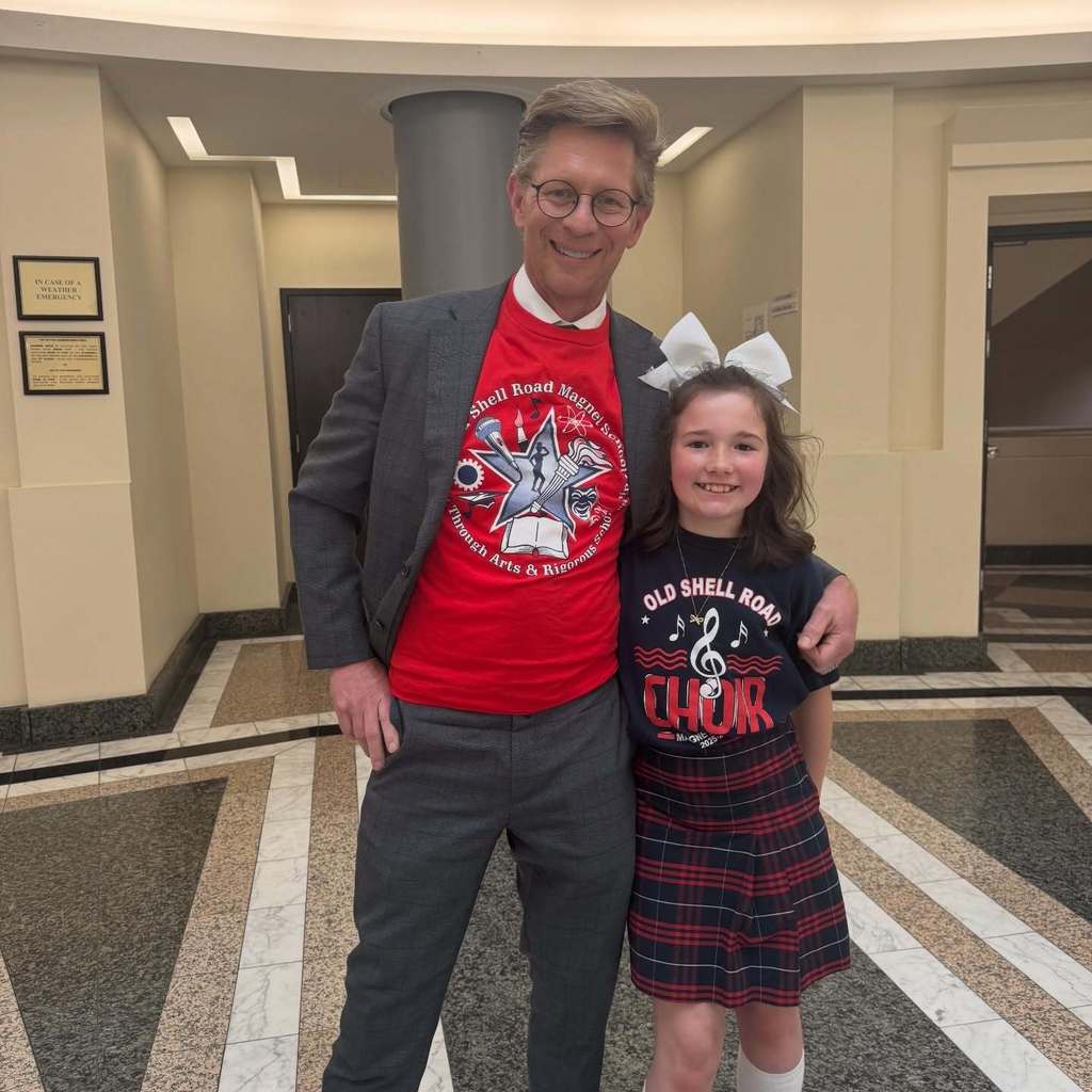 State Education Superintendent Dr. Eric Mackey stands with an Old Shell Road student