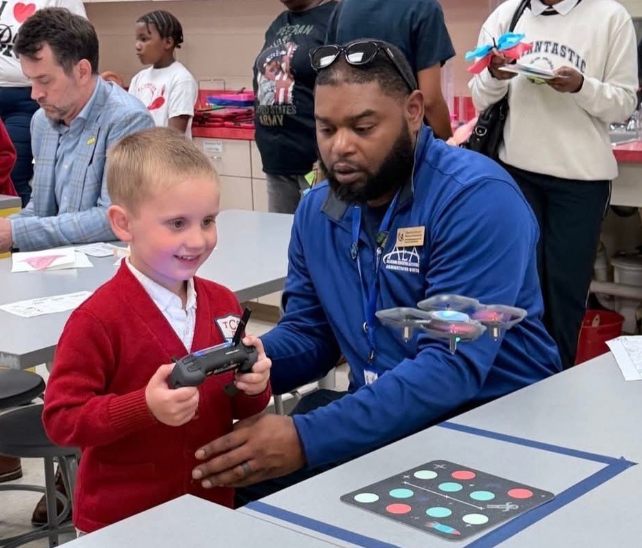 A boy operates a drone while a man looks on