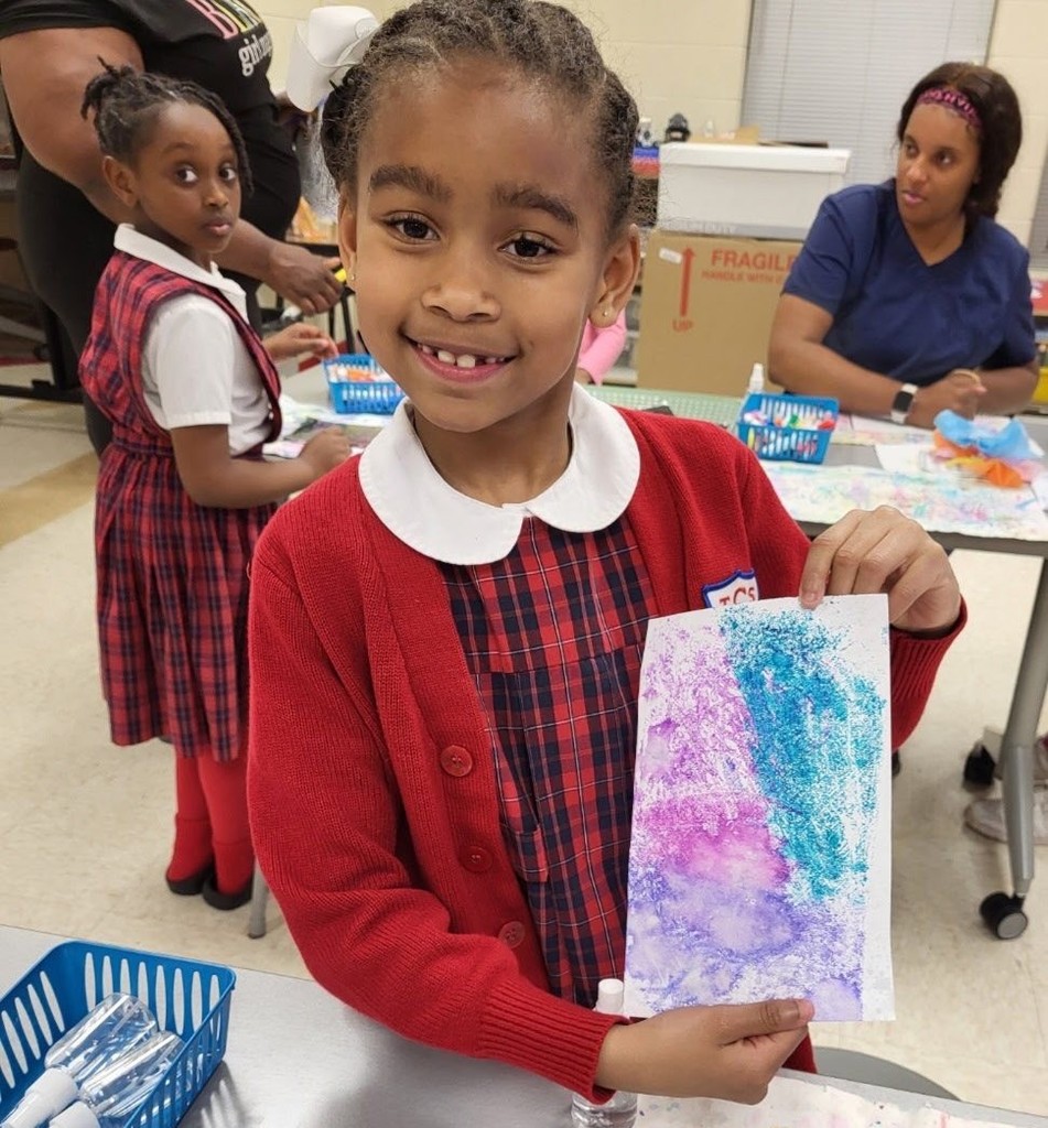 A girl holds up her artwork
