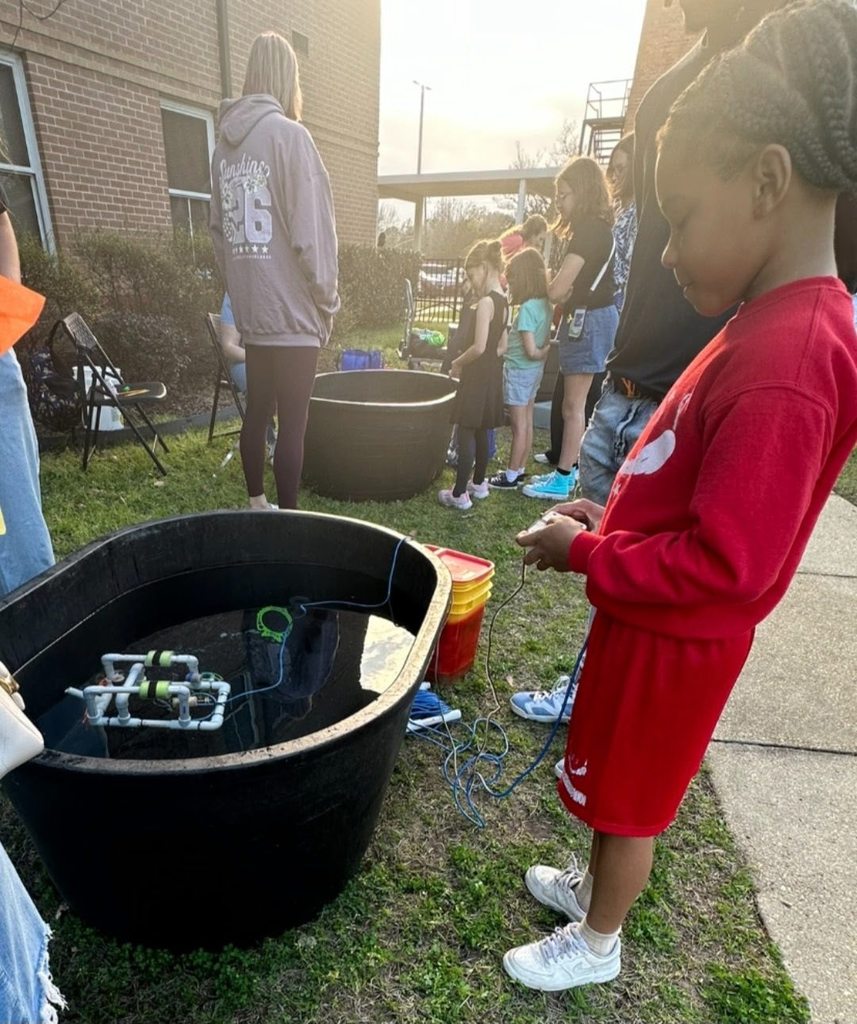 A boy plays with a submersible ROV in a tub of water