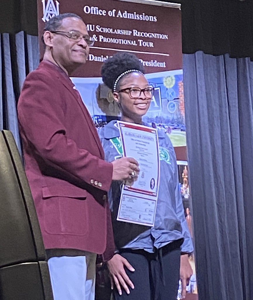 A man in a maroon blazer stands with a Vigor student, holding a certificate