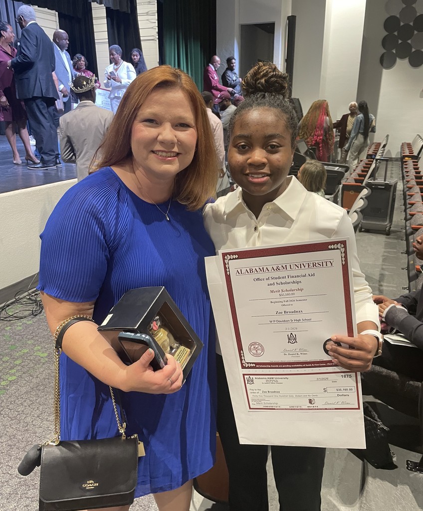 A woman in a blue dress stands with a Davidson student holding a certificate
