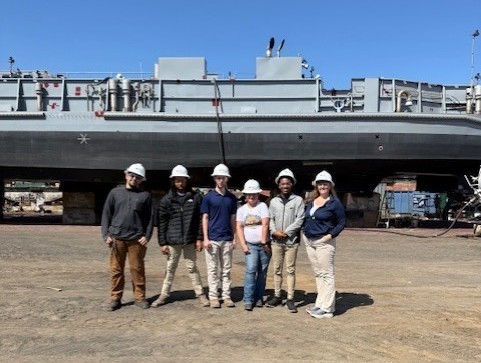 Murphy High students in hardhats standing in front of a ship