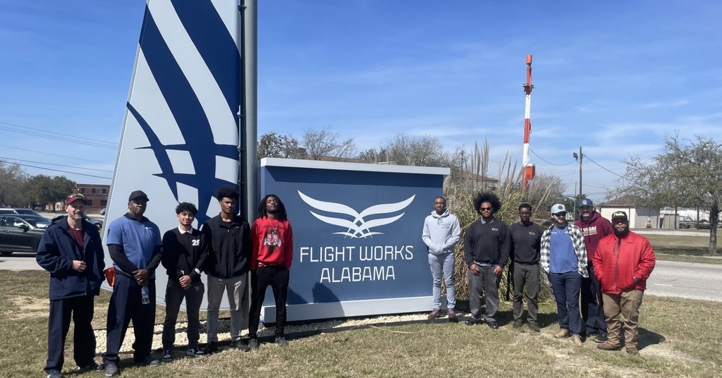 B.C. Rain students standing by the Flight Works Alabama sign