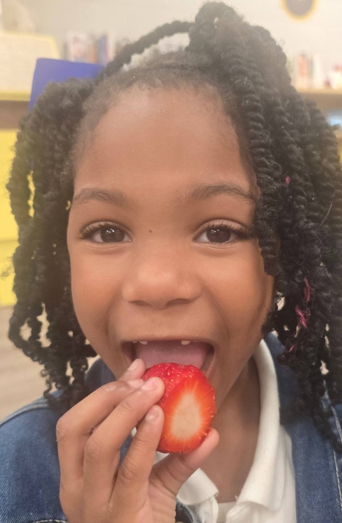 A girl biting into a strawberry