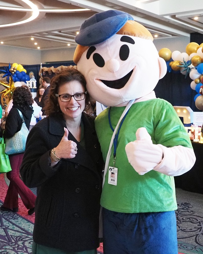 The Collier Elementary principal standing with a mascot and giving a thumbs up