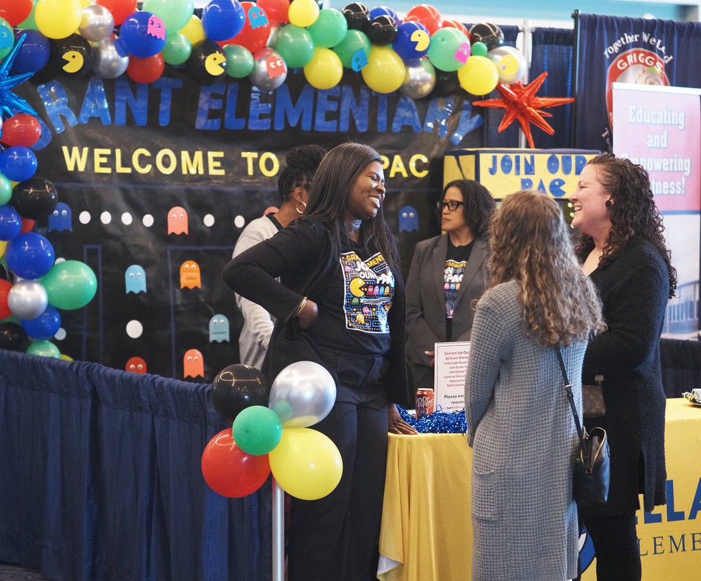 Two job-seekers talking with a representative of Ella Grant Elementary