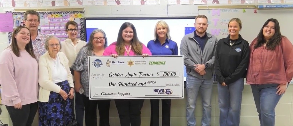 Rebecca Waldo holds an oversized check and stands with her family members and representatives of WKRG