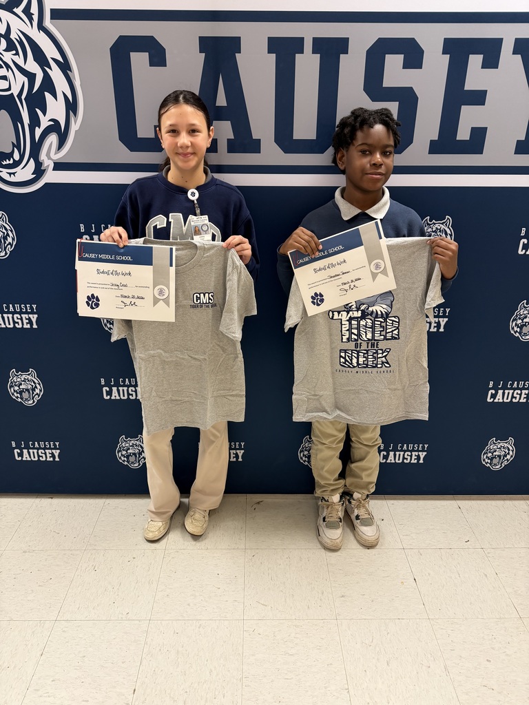 2 students holding up t-shirts and certificates