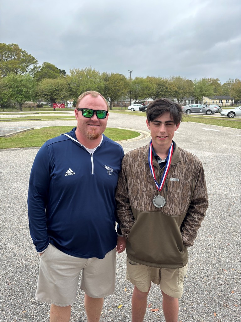 A boy with a medal around his neck standing with his teacher