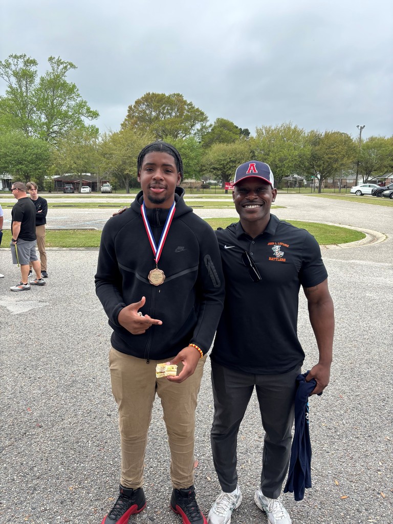 A boy with a medal around his neck standing with his teacher