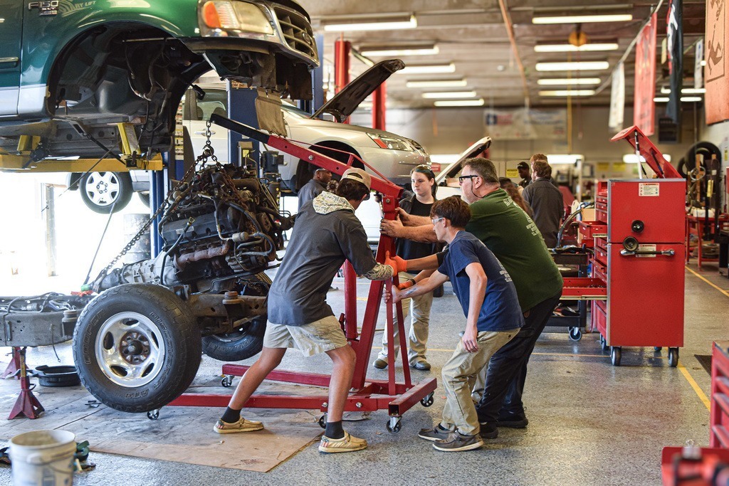 Four Faulkner students hoist an engine with a crane
