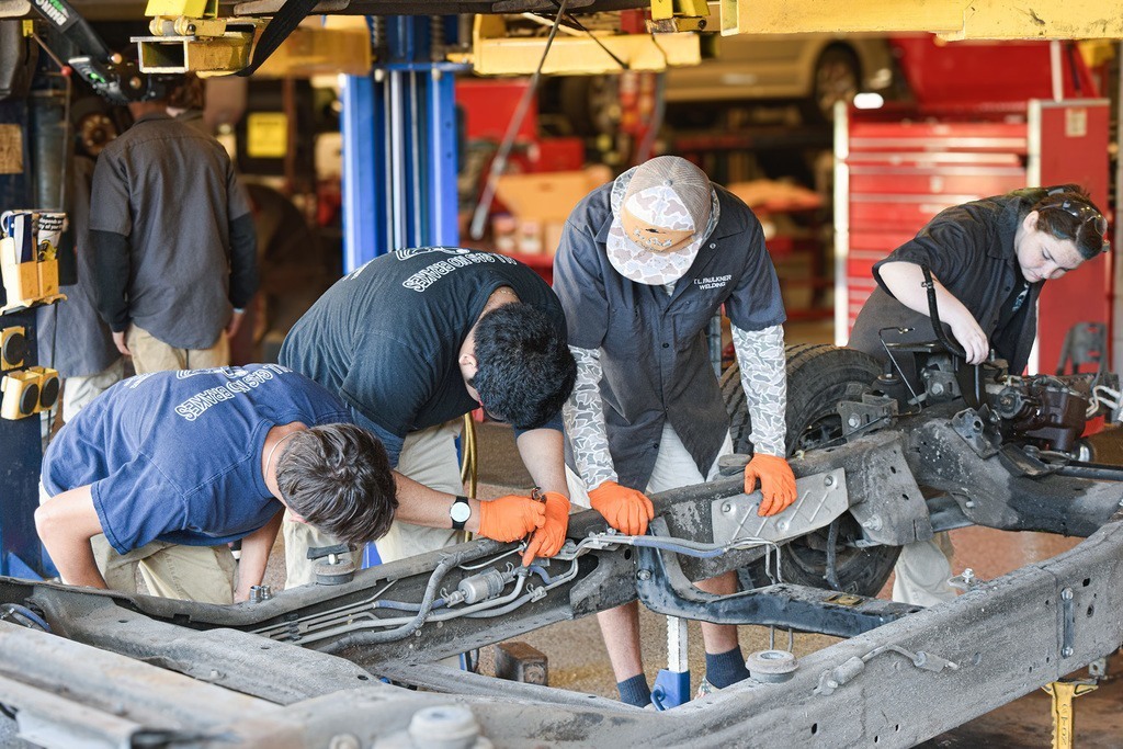 Four Faulkner students examine a truck chassis
