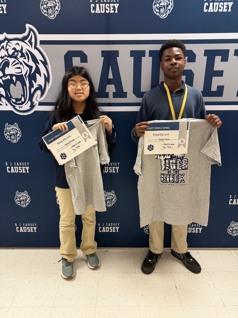 2 students holding up t-shirts and certificates
