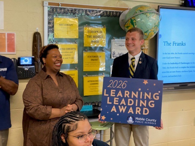 Ben Stringfellow accepts a Learning Leading Award sign from Phillips Principal Johnnie Williams