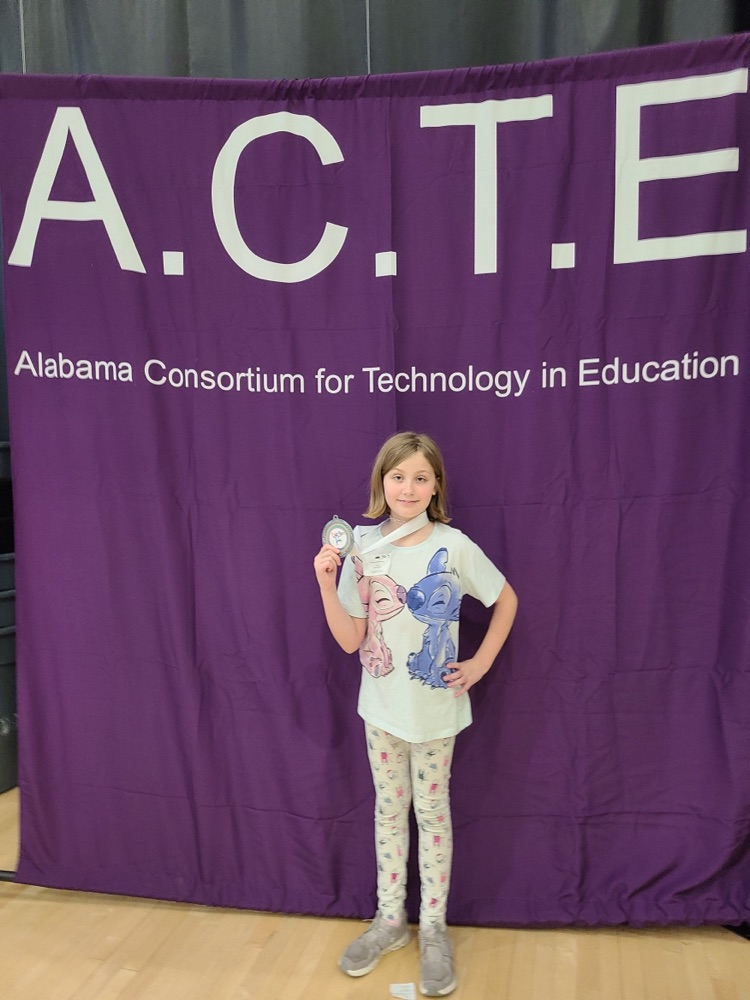 female student holding 2nd place medal in front of ACTE banner