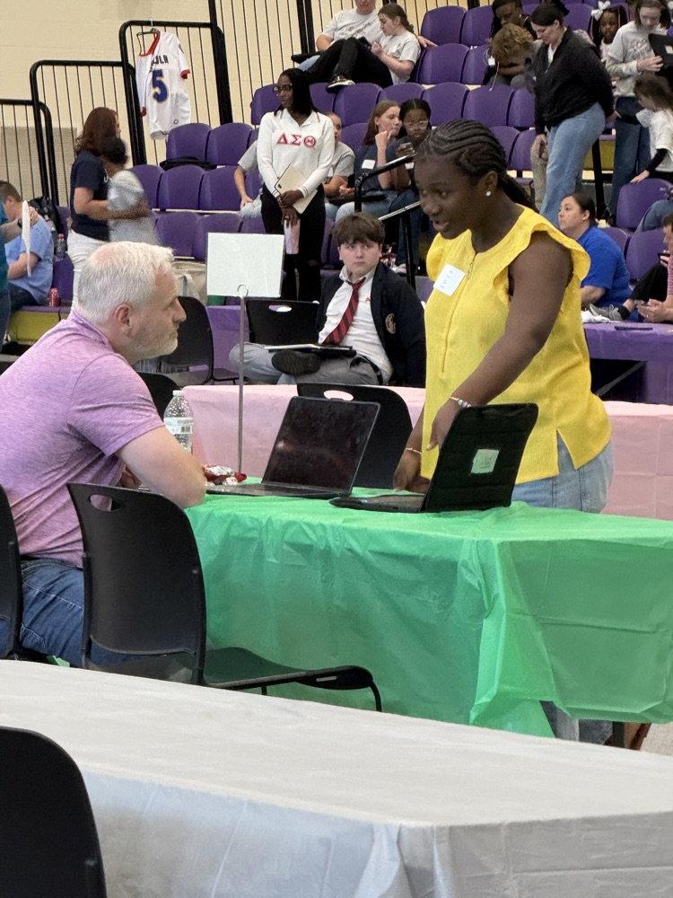 student presenting computer project to a tech fair judge
