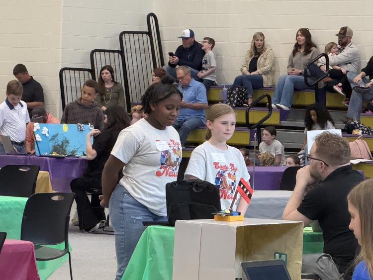 two female students presenting their video project to a judge 