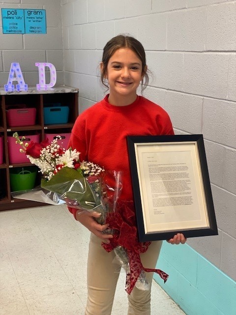 Anniston Byrd, holding flowers and a framed copy of her nomination letter