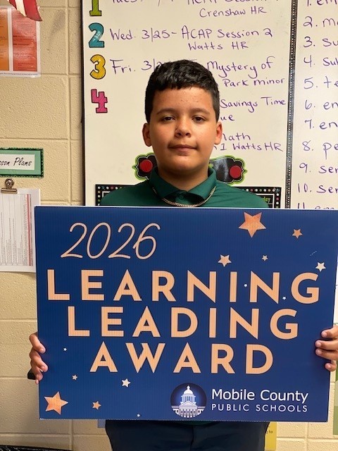 Rylan Besaw holds a Learning Leading Award sign
