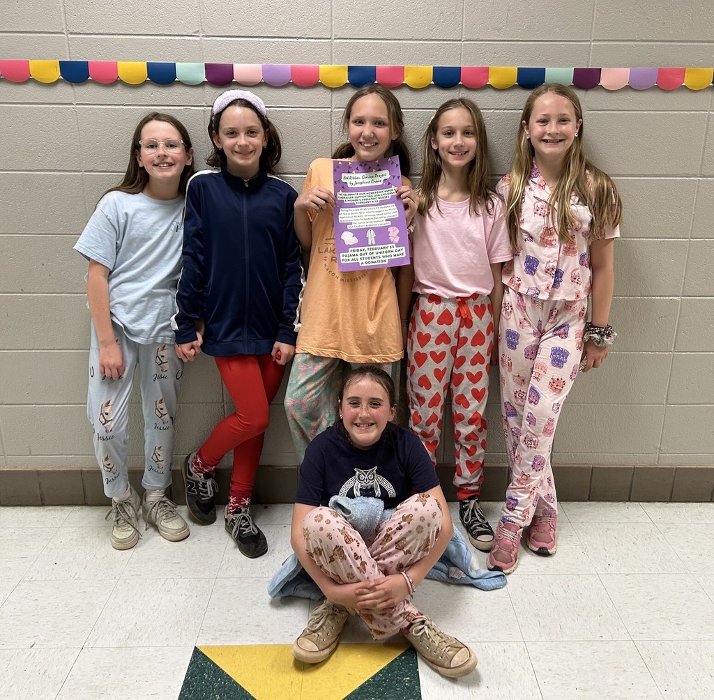 A group of elementary school girls wearing pajamas in a hallway