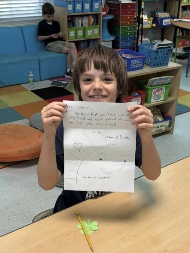 A Collier Elementary student holding up a letter