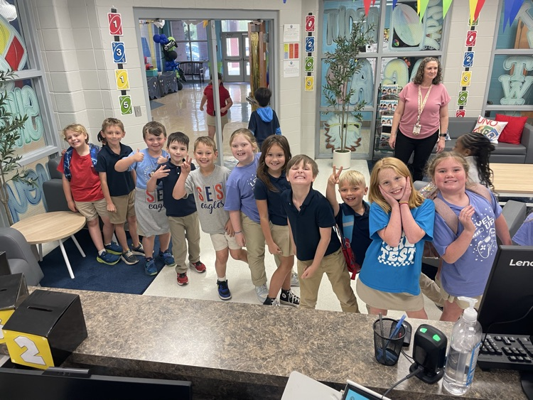 a line of second grade students do silly poses as they wait for the prize cart