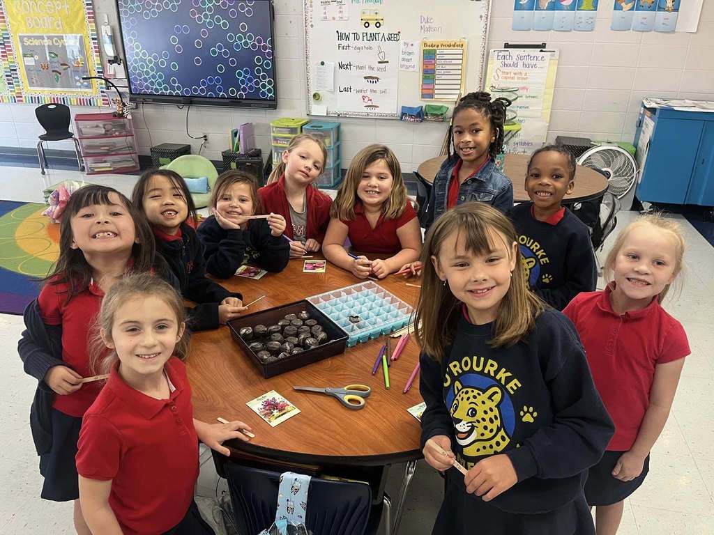 A group of O'Rourke Elementary students stand around a table with some plant seedlings