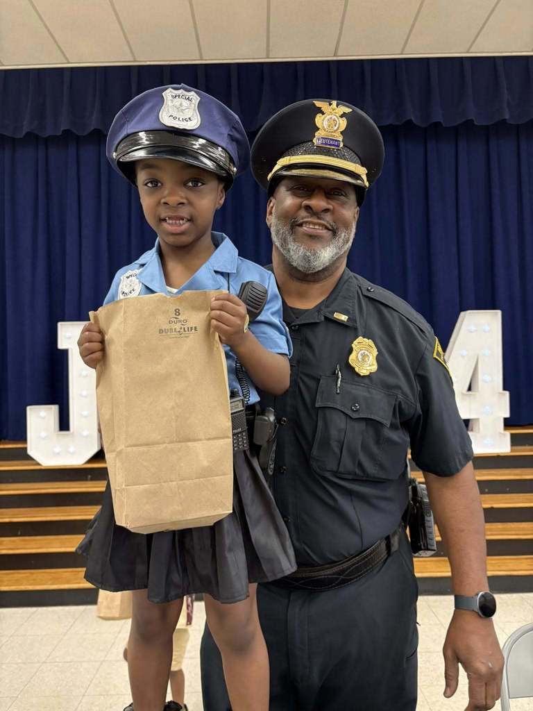 A boy dressed like a police officers stands with a real police officer