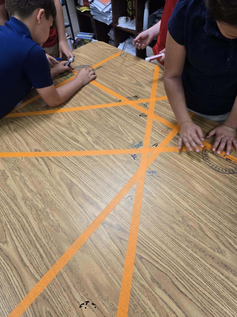 Mrs Holland's class measured acute, right, and obtuse angles using protractor on our classroom tables.