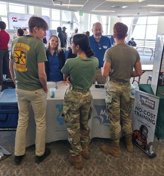 Exhibitors talk with three Theodore students in JRTOC fatigues