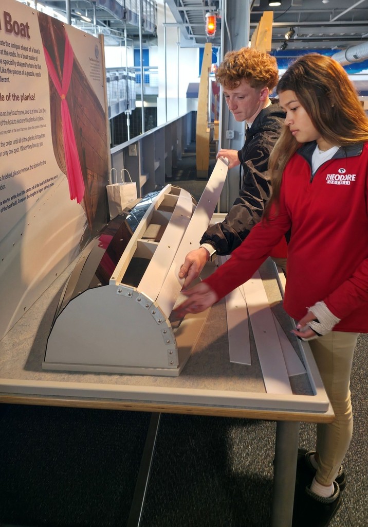 Two Theodore students work with a hands-on boat-building exhibit