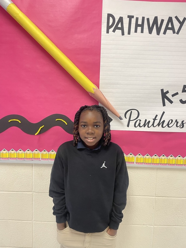 Student of the Month standing in front of a bulletin board that reads "Pathway K-5 Panthers" 