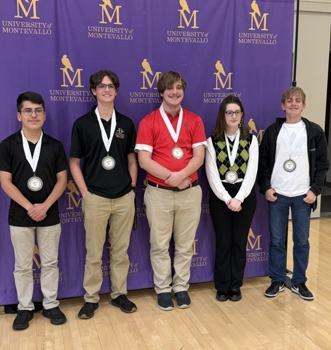 Five students standing in front of a Montevallo backdrop