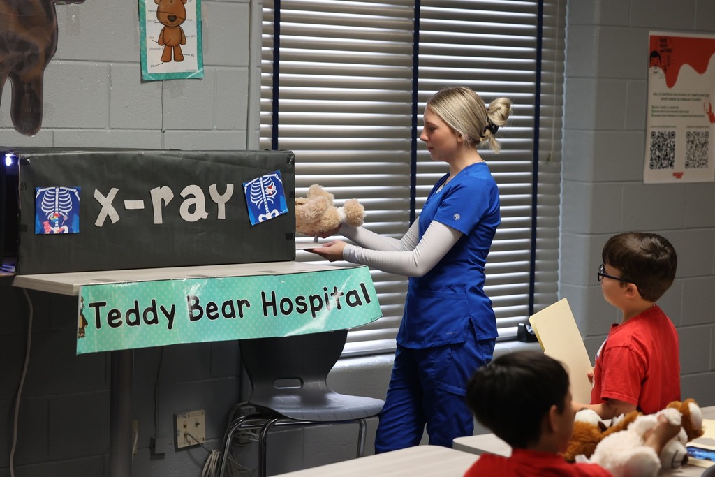 A Bryant High student puts a teddy bear in a makeshift "X-ray machine" while a Castlen Elementary student watches