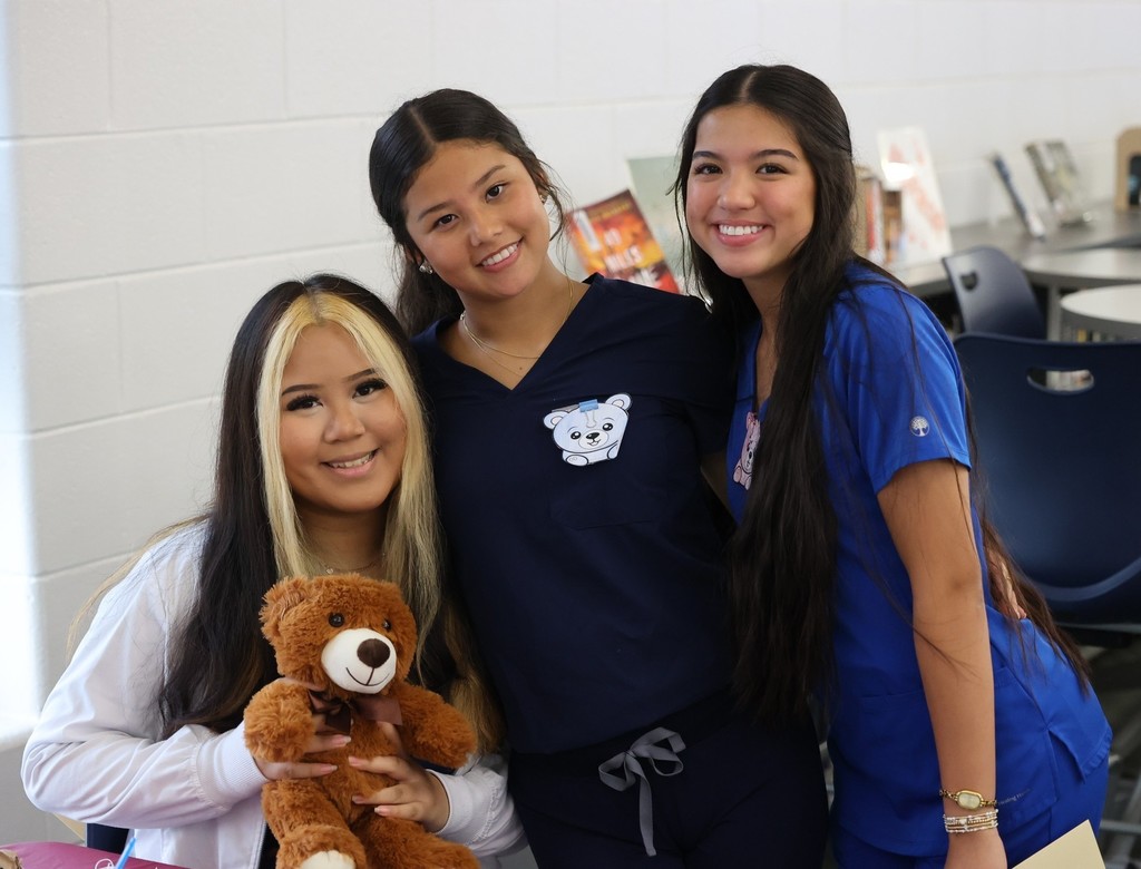 Three Bryant High health sciences students, with a teddy bear