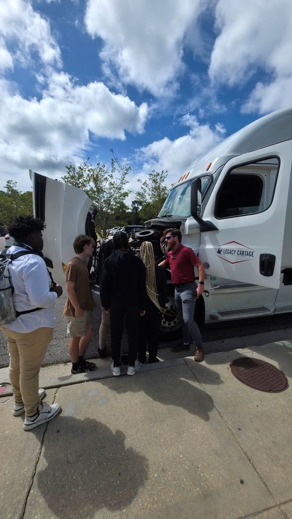 The instructor points out parts under the hood of the Legacy Cartage truck.