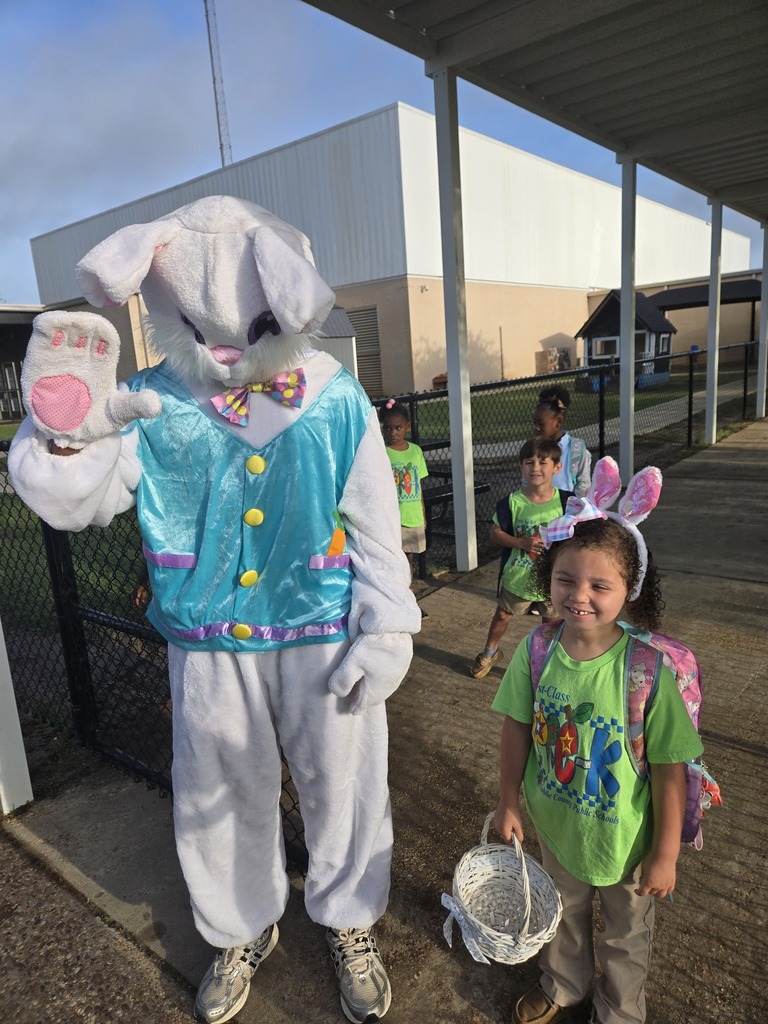 An adult dressed as the Easter Bunny stands with a Pre-K student holding a basket