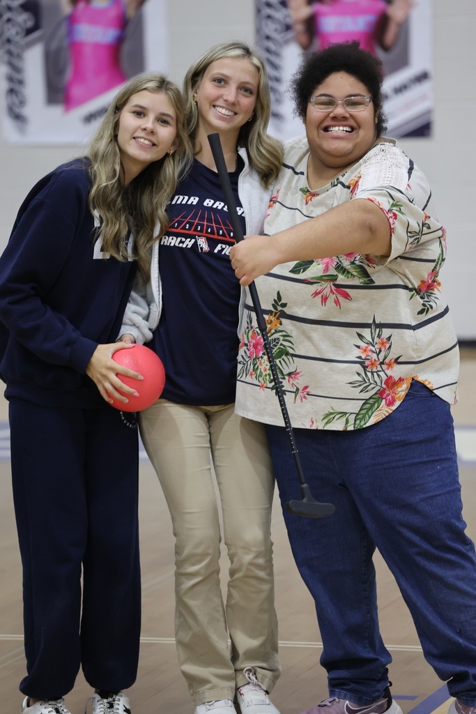 Three Alma Bryant High students smiling, with one holding a putter